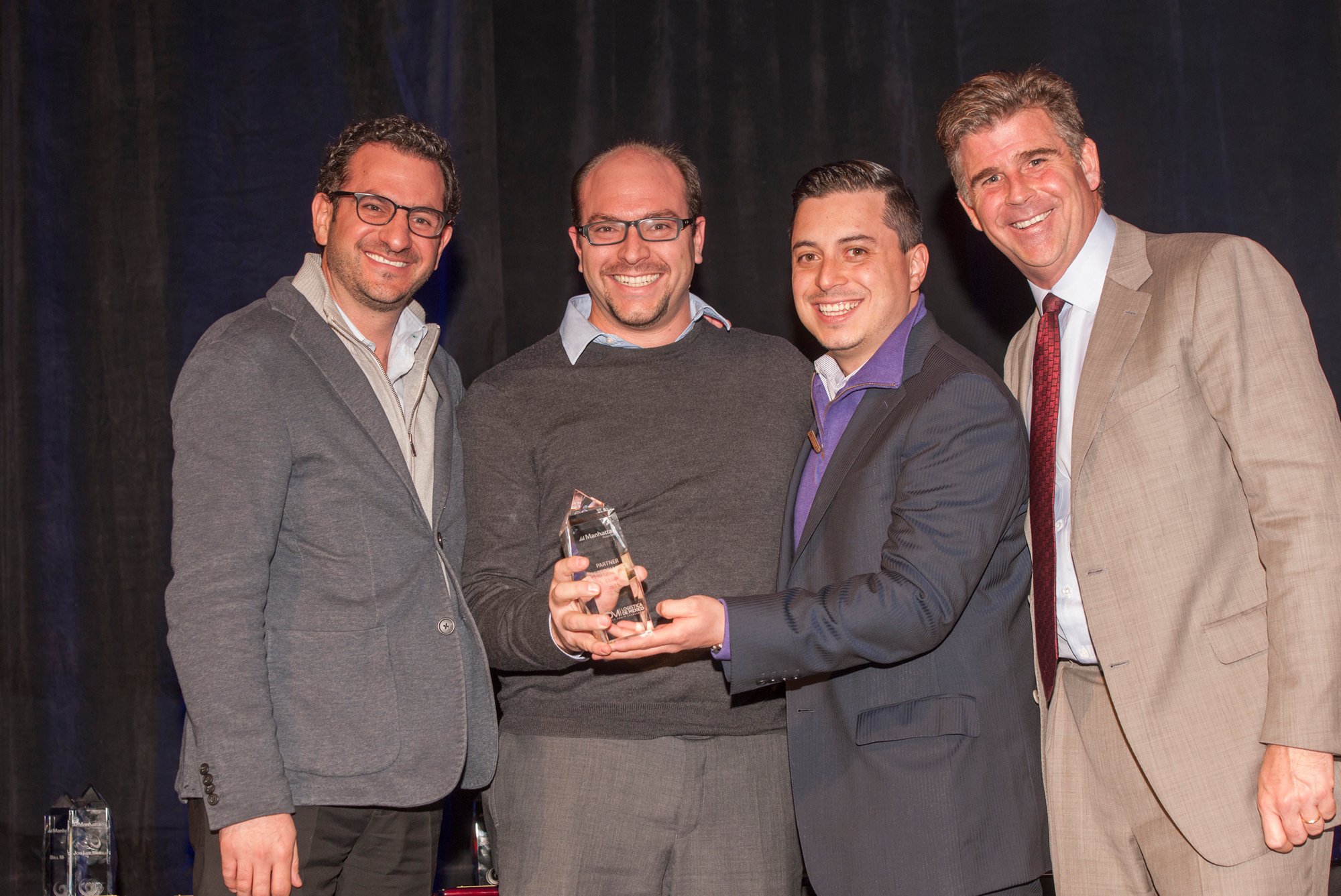 Photo of four event attendees accepting an award from the Manhattan Associates employee event.