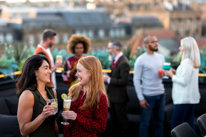 Young female professionals having cocktail hour at corporate event